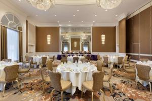 uma sala de banquetes com mesas, cadeiras e lustres em Hilton Philadelphia City Avenue em Filadélfia