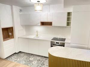 uma cozinha branca com um lavatório e um balcão em Appartement 4P U Arena em Nanterre