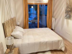 um quarto com uma cama branca em frente a uma janela em Appartement 4P U Arena em Nanterre