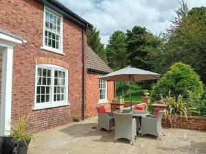 a patio with a table and chairs and an umbrella at Clumber Lane End Farm in Worksop