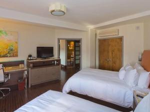 a hotel room with two beds and a flat screen tv at The Tudor Arms Hotel Cleveland - a DoubleTree by Hilton in Cleveland