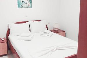 Una cama con sábanas blancas y dos toallas. en Zorbas House en Heraclión