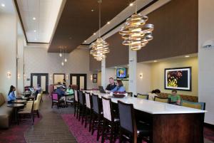 restauracja z barem i ludzie siedzący przy stolikach w obiekcie Hampton Inn & Suites Saginaw w mieście Saginaw