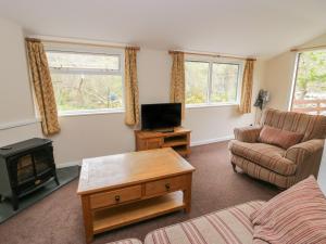 a living room with a couch and a tv at Chestnut Timber Lodge in Keswick