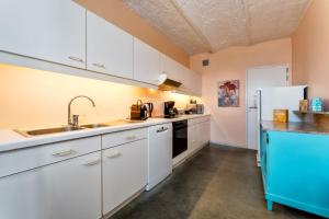 a kitchen with white cabinets and a sink and a refrigerator at Guesthouse Polderlicht in Blankenberge