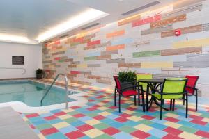 een poolkamer met een tafel en stoelen naast een zwembad bij Hilton Garden Inn Burlington Downtown in Burlington