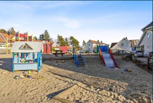 a playground with play equipment in the sand at Nydelig hus med utsikt in Kristiansand