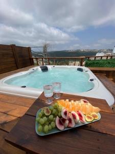 a plate of fruit on a table next to a swimming pool at T&S suite in Dāliyat el Karmil