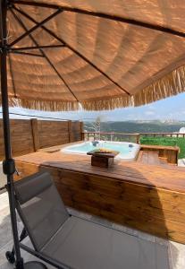 una gran terraza de madera con bañera de hidromasaje y silla en T&S suite en Dāliyat el Karmil