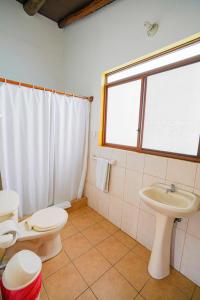 baño con 2 aseos, lavamanos y ventana en Galapagos Verde Azul en Puerto Ayora