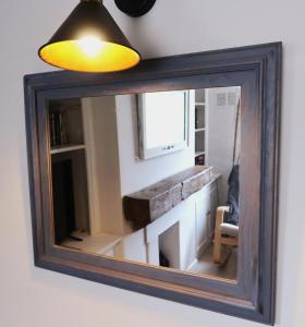 a mirror hanging on a wall with a light at Boutique cottage in the heart of Winchcombe in Winchcombe