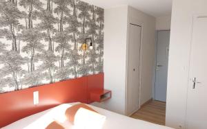 a bedroom with a wall with a mural of trees at Logis Hôtel Vannes Nord Le Clos Des Hortensias in Locqueltas
