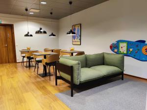 - un salon avec un canapé, des tables et des chaises dans l'établissement Hiisi Hotel Helsinki Jätkäsaari, à Helsinki