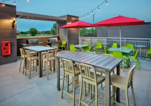 un patio con mesas, sillas y sombrillas rojas en Home2 Suites By Hilton Wichita Falls, Tx, en Wichita Falls