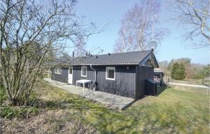 una casa negra con terraza en un patio en Stunning Home In Grenaa With 3 Bedrooms And Wifi, en Fuglsang