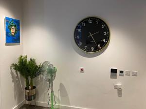 a clock on a wall with a plant and a fan at Unique comfortable Apartment in Abbey Wood