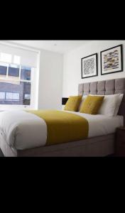 a bedroom with a large bed with yellow sheets and a window at Unique comfortable Apartment in Abbey Wood