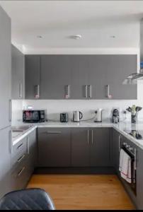cocina con electrodomésticos blancos y suelo de madera en Unique comfortable Apartment, en Abbey Wood