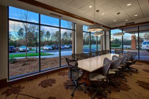 une salle de conférence avec une table, des chaises et des fenêtres dans l'établissement Hilton Garden Inn Durham-University Medical Center, à Durham