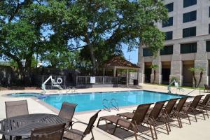 a pool with chairs and a table and a building at Hilton New Orleans Airport in Kenner