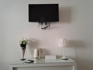una TV a parete con tavolo e lampada di Star suite ☆ a Catania Altre 4 foto