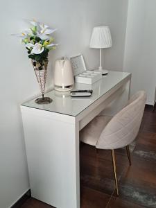 una scrivania bianca con un telefono e fiori di Star suite ☆ a Catania