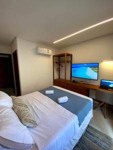 a bedroom with a large bed and a desk with a television at Reserva BG - Vila Caju - Vista Mar - Barra Grande in Barra Grande