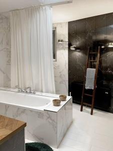 uma casa de banho com uma banheira, um lavatório e um espelho. em Loft House, Pool & Garden em Montreuil