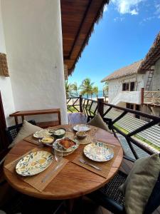 a wooden table with plates of food on a balcony at Reserva BG - Vila Caju - Vista Mar - Barra Grande in Barra Grande