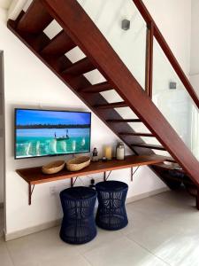 a living room with a tv under the stairs at Reserva BG - Vila Caju - Vista Mar - Barra Grande in Barra Grande