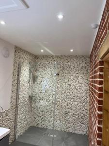 a bathroom with a shower and a brick wall at Grange Farm Barn, Filby in Filby