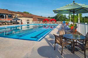 a swimming pool with tables and chairs and an umbrella at DoubleTree by Hilton Hotel St. Louis - Chesterfield in Chesterfield