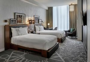 um quarto de hotel com duas camas e uma cadeira em LondonHouse Chicago, Curio Collection by Hilton em Chicago