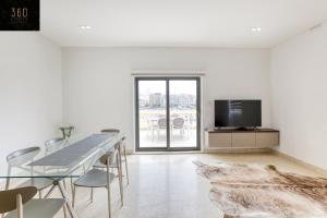 Una habitación blanca con una mesa de comedor y un televisor. en Marina VIEW APT SLPs 9 with private terrace & BBQ by 360 Estates, en Taʼ Xbiex