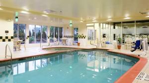 einen Pool in einem Hotel mit Stühlen und Tischen in der Unterkunft Hilton Garden Inn Secaucus/Meadowlands in Secaucus