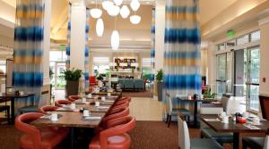 un restaurante con mesas de madera y sillas naranjas en Hilton Garden Inn Secaucus/Meadowlands en Secaucus