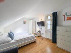 a white bedroom with a bed and a tv at Penzion Portus in Bratislava