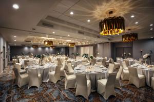 una sala de banquetes con mesas y sillas blancas y una lámpara de araña en Somerset Hills Hotel, Tapestry Collection by Hilton, en Basking Ridge