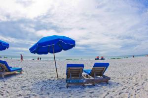 two chairs and an umbrella on a beach at Hilton Garden Inn Orange Beach in Gulf Shores