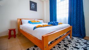 1 dormitorio con 1 cama con cortinas azules y ventana en Cozy Haven en Nanyuki
