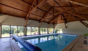 an indoor swimming pool with wooden ceilings and windows at Ma Tranquillite in Courpière