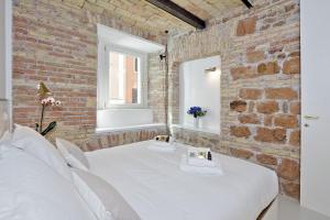 ローマにあるLaterano Charmeのレンガ壁の客室で、白いベッド1台、窓が備わります。