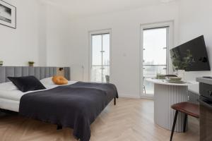 1 dormitorio con cama, mesa y ventanas en Wola Business Studios Kasprzaka by Renters, en Varsovia