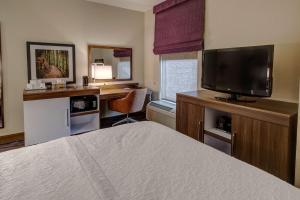 een slaapkamer met een bed en een bureau met een televisie bij Hampton Inn Arkadelphia in Arkadelphia