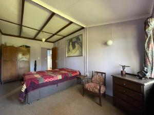 a bedroom with a bed and a chair and a dresser at Thathe Dam Lodge in Vhutandabos