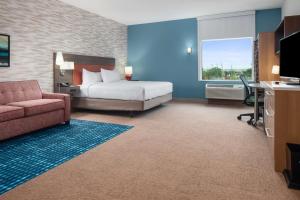 Habitación de hotel con cama, sofá y escritorio en Home2 Suites By Hilton Rowlett Rockwall Marina, en Rowlett