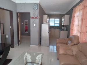 uma sala de estar com dois sofás e uma cozinha em Kadichueni Guest House em Zeerust