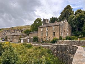 an old stone village with a castle in the background at Bridge House in Muker
