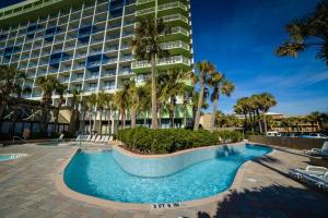 a swimming pool in front of a building with palm trees at Oceanfront Condo with Amazing Oceanfront Views in Myrtle Beach