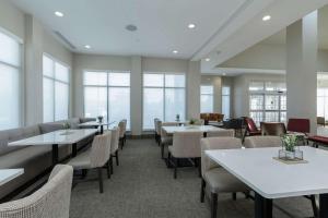 a dining room with tables and chairs and windows at Hilton Garden Inn Elkhart in Elkhart